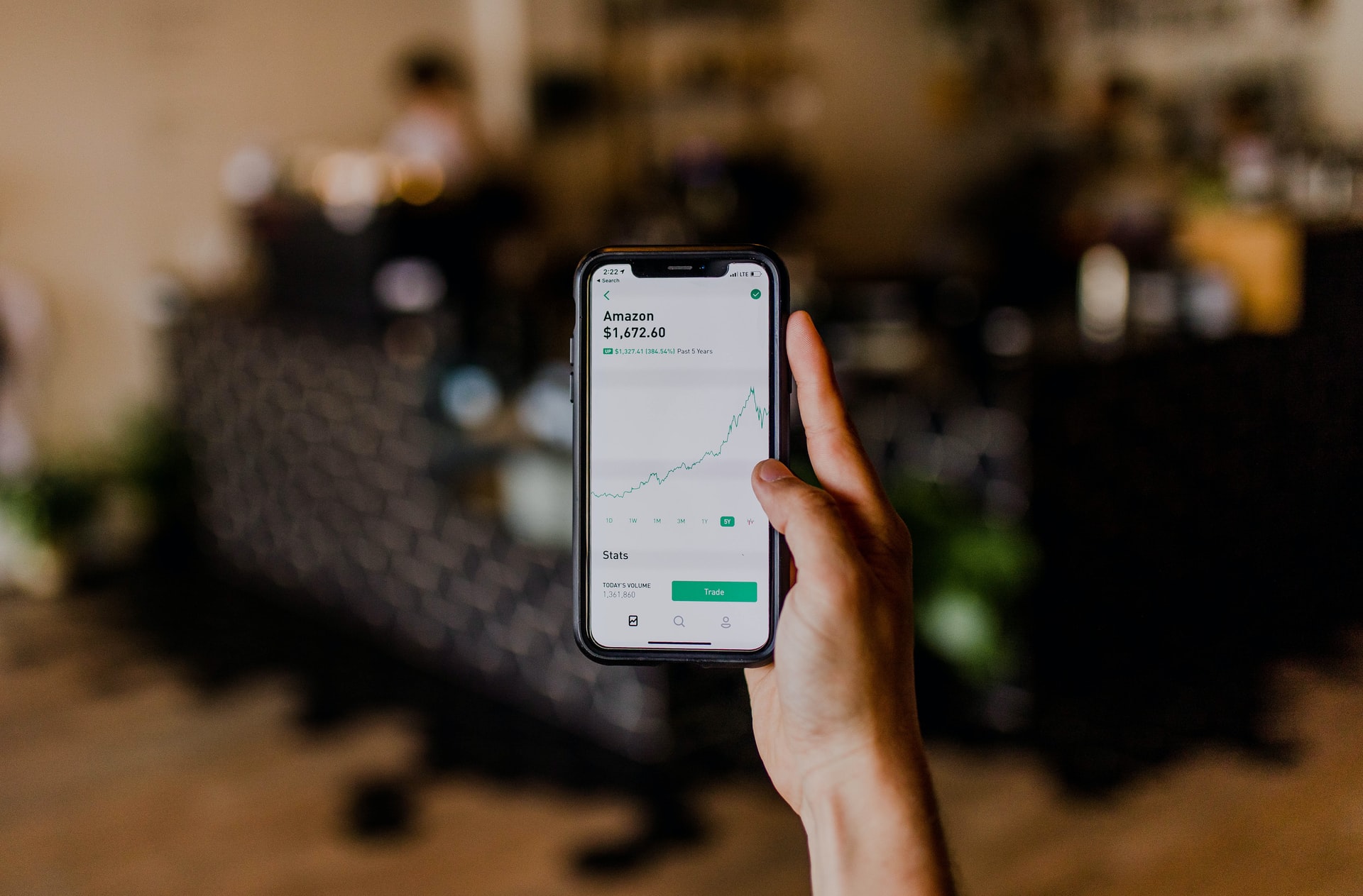 Person holding phone with stock chart on screen.