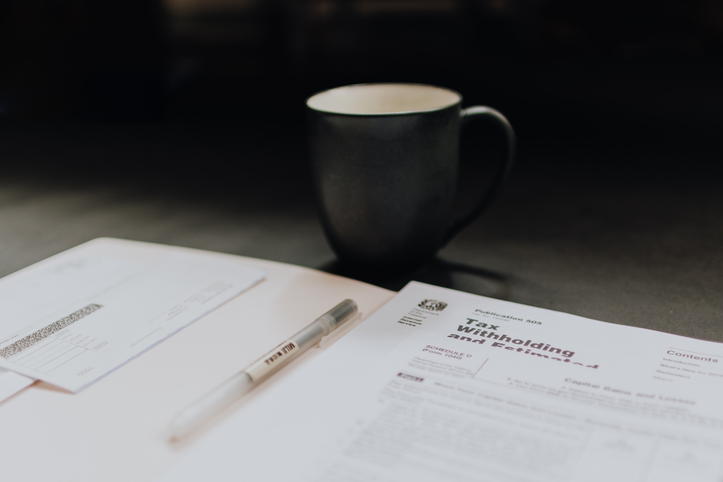 A coffee cup sitting on a table behind tax forms